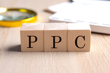 PPC on wooden cubes with magnifier and calculator, financial concept background