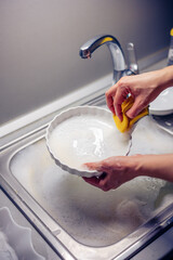 Close up of woman housewife is doing the dishes at home kitchen by using wash sponge and dishwashing