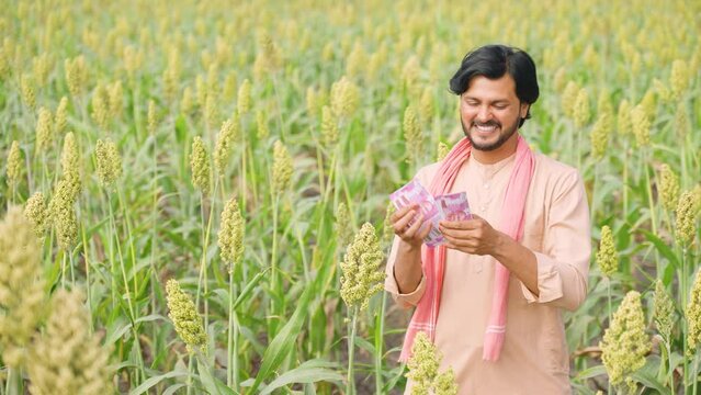 Happy farmer couting money or currency at agricultural farmland - concept of profit or earnings, banking or financial and agri business