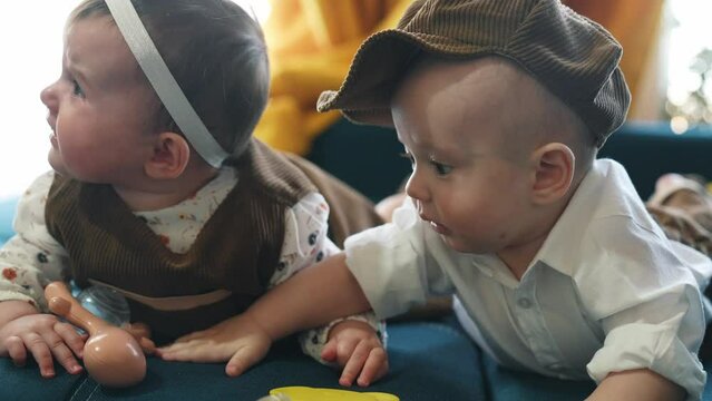 twin babies in retro clothes. brother and sister a twins lifestyle kids sit on the couch in retro clothes cap play among themselves. happy family kid dream twin concept