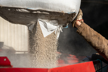 Epandage d'engrais Bio3G stimulateur de croissance qui augmente l'activité microbienne du sol. Sac big bag, remplissage de l'épandeur