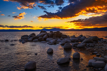Sunset above rocky beach of Lake Tahoe in California