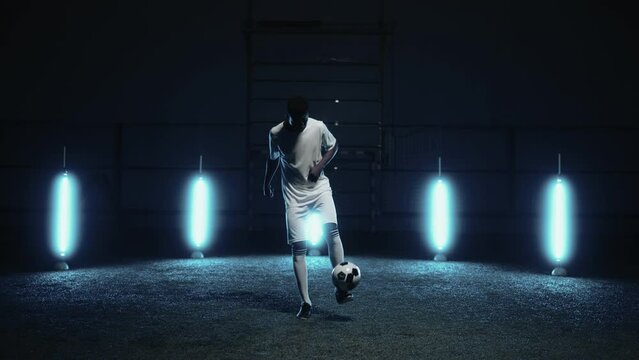 african athlete playing football alone at night, portrait of man practicing keepie uppie exercise
