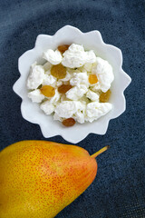 Fresh large cottage cheese with raisins and fresh pears in a white plate