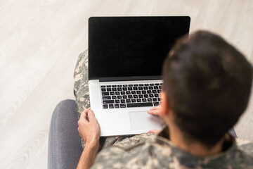 military man in uniform looking at laptop