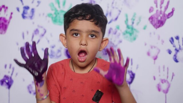 grimacing Cheerful kid showing painted hands by looking camera at home - concept of imagination, mischief and playful childhood.