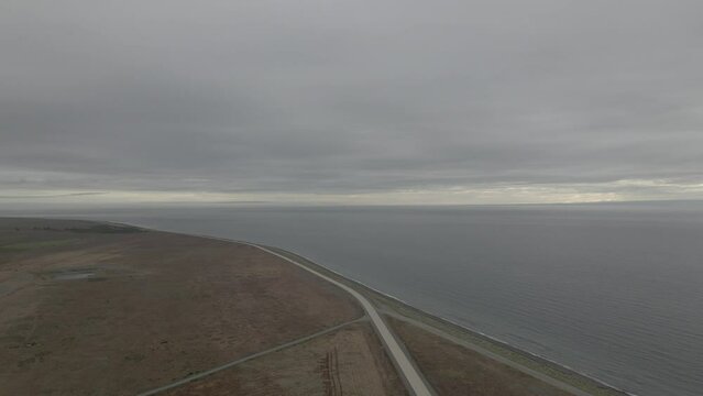 Autos pasando por la carretera a un costado del mar en el estrecho de Magallanes