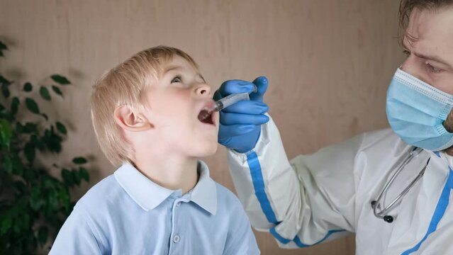 Kid getting polio drops. Doctor making to Child Oral Vaccination against infection. Little Blonde Hair Boy at Hospital. Children health care and disease prevention. Via of Polio Vaccine. Immunization.