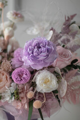 Beautiful composition with peonies and roses in a purpl box on pink chair. Bouquet of tenders peonies a girl for mother's day, valentine's day, Woman's day 8 march.