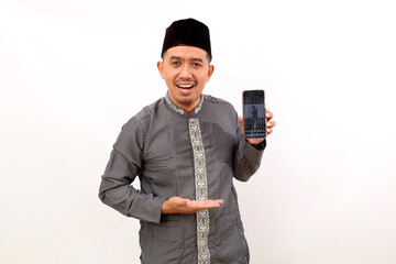 Happy asian muslim man standing while showing blank cellular phone screen. Isolated on white background