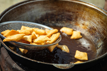 Baursaks are roasted in a large cauldron outdoor.