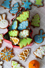 Fototapeta na wymiar Ginger cookies in shape of rabbits,Christmas trees and snowflakes with sugar icing - light blue, green, white.
