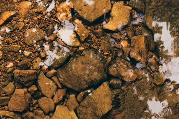 Background of clear river water with mossy rocks at the bottom.