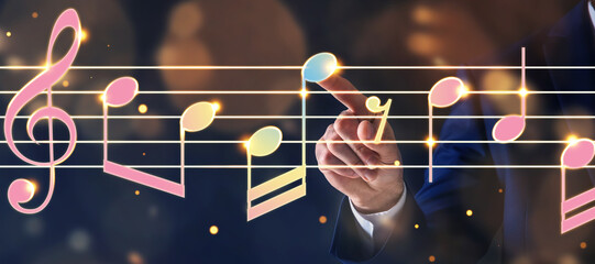 Musician pointing at staff with music notes and symbols on color background, closeup. Banner design