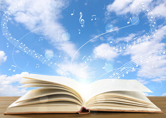 Music flowing from book. Musical symbols flying over tome on wooden table against sky