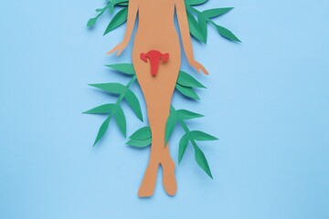 Woman's health. Female paper figure with uterus and leaves on light blue background, flat lay
