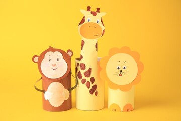 Obraz premium Toy monkey, giraffe and lion made from toilet paper hubs on yellow background. Children's handmade ideas