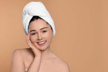 Portrait of attractive young woman with towel on beige background, space for text. Spa treatment