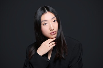 Portrait of beautiful young Asian woman on black background