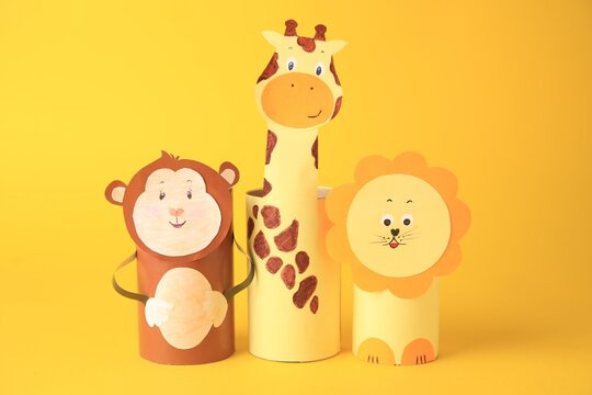 Toy monkey, giraffe and lion made from toilet paper hubs on yellow background. Children's handmade ideas