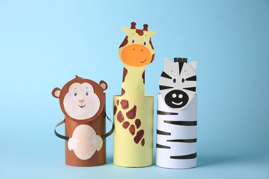 Toy monkey, giraffe and zebra made from toilet paper hubs on light blue background. Children's handmade ideas