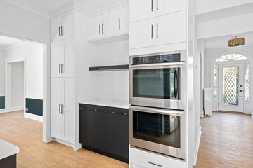 Modern Black and White White Kitchen with Stainless Steel Luxury Appliances. Contemporary dual tone cabinets with white marble slab backsplash. Empty Kitchen for virtual staging.