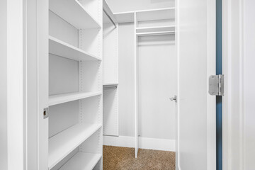 Modern Bedroom Walk In Closet. Empty primary closet with shelving and clothing racks. Vacant room for virtual staging.