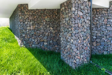 Gabions in the finishing of the foundation of a country house. Natural stone in facade decoration.