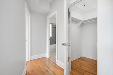 Modern Bedroom Walk In Closet. Empty primary closet with views into en suite bathroom. Vacant room...