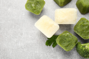 Frozen cauliflower and broccoli puree cubes on light grey table, flat lay. Space for text