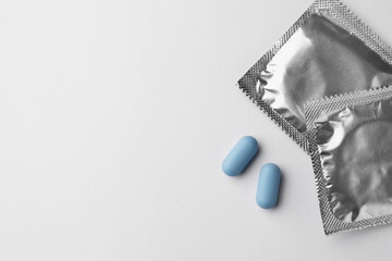 Pills and condoms on white background, flat lay with space for text. Potency problem