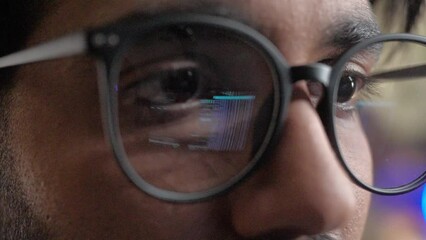 Close-up view of young man wearing glasses with reflection of screen with binary code. Professional male developer programming on computer sitting in office of modern IT company. - Powered by Adobe