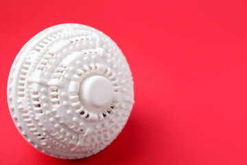 Laundry dryer ball on red background, space for text