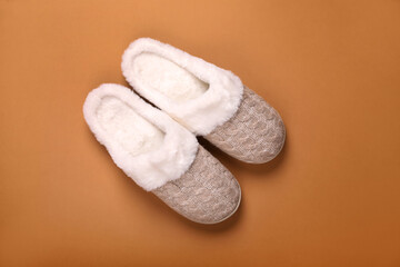 Pair of beautiful soft slippers on light brown background, top view