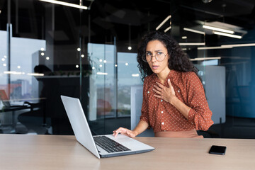 Fototapeta na wymiar Anxious and scared business woman working inside office, Hispanic woman panic attack and breathing problem, female worker with laptop working.