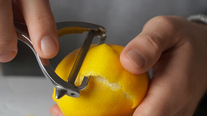 Man peeling lemon at table, closeup view