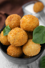 Bowl of delicious fried tofu balls with basil on textured table, closeup