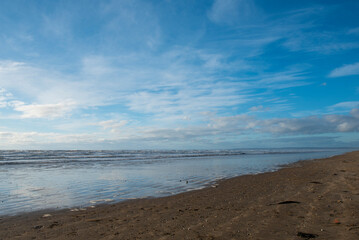 Landscape image of Llanelli beach with blue cloudy sky on a winters day, taken with copy space 
