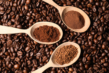 Spoons with different types of coffee on roasted beans, flat lay