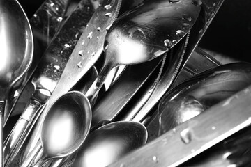 Washing silver spoons, forks and knives, closeup