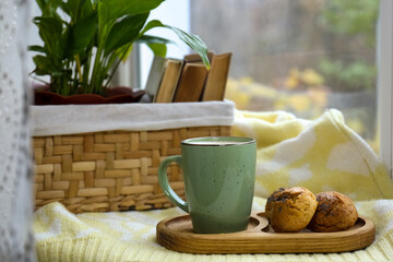 Cup of tasty hot drink and cookies near books on windowsill. Autumn coziness