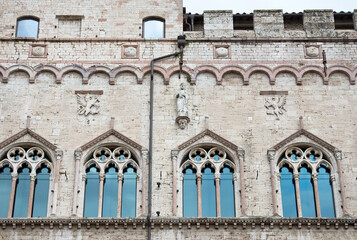 Fototapeta na wymiar Palazzo dei Priori in Piazza IV Novembre a Perugia. Statua di San Pietro sulla facciata con ai lati due grifi. Finestre trifore gotiche