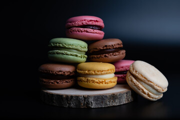 Obraz na płótnie Canvas Macarons cookie dessert from France in a stack on wooden board and black background