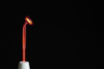 Working high frequency darsonval device on black background, closeup. Space for text