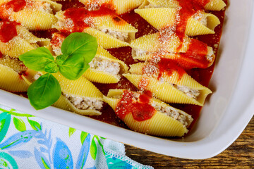 Served in ceramic pan conchiglioni are stuffed with ricotta cheese on tomato sauce