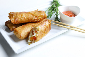 Involtini primavera fritti con salsa di peperoncino dolce su sfondo bianco. Cucina asiatica.