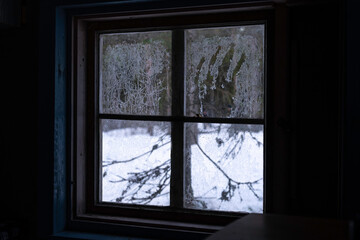 Spooky handprint on a window in an old, isolated cabin in the woods. Finland