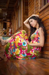Fototapeta premium relaxed sitting young latin woman wearing colorful dress and with long hair, lifestyle and natural beauty, model portrait