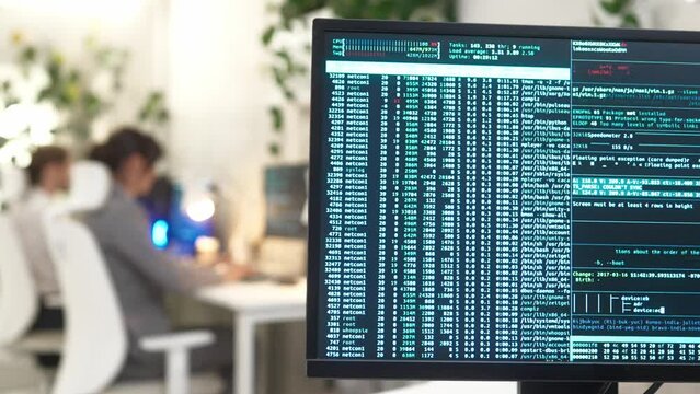 Computer monitor with binary code large database on table in modern office of international IT company with professional qualified workers on background working wearing smart style clothes.