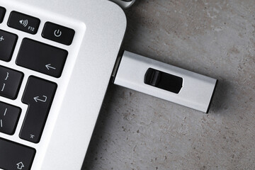 Usb flash drive attached into laptop on light grey table, top view